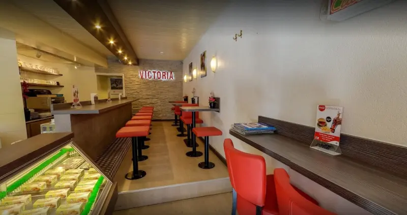 De lange bar met rode krukken en het verlichte Victoria-logo op de achterwand