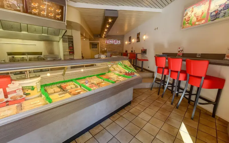 De toonbank met gevulde snackvitrine en rode barkrukken