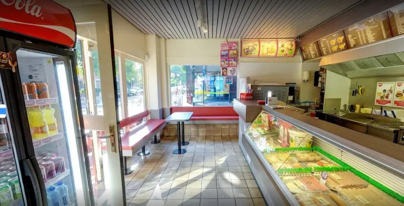 De zaak gezien vanaf de ingang: koelkast met frisdrank, de vitrine en de menuborden
